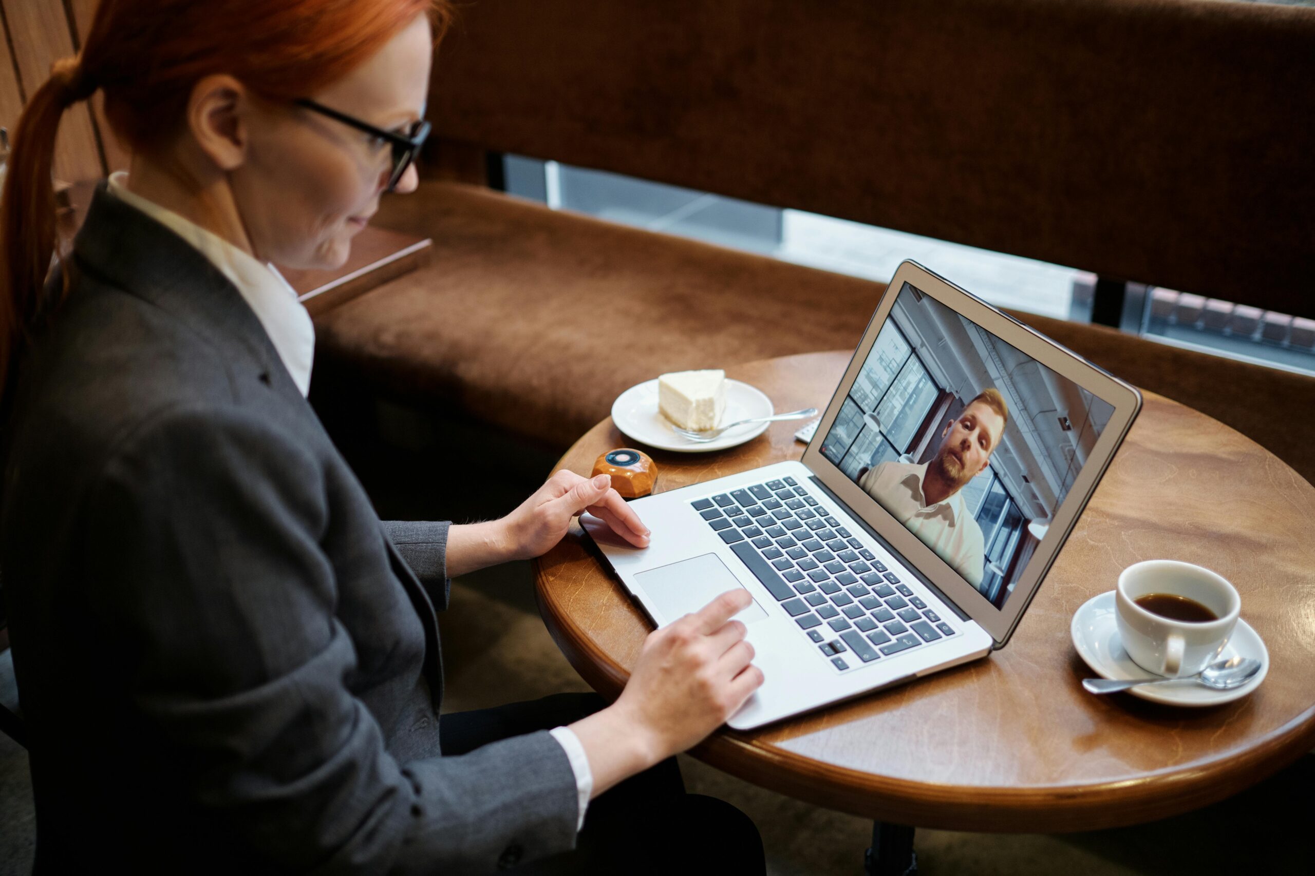 a woman looking at her laptop in a coffee shop planning on engaging with a business online